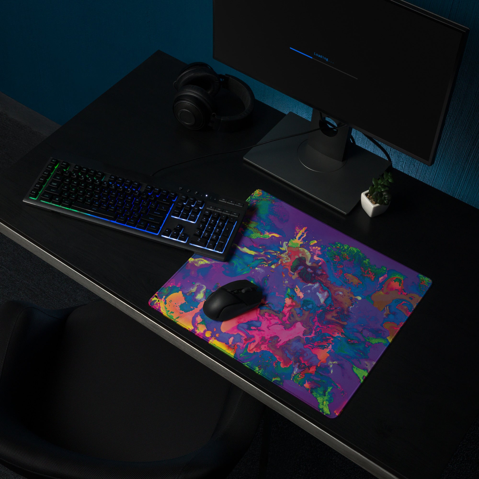 Colorful mouse pad on a dark desk with a computer setup
