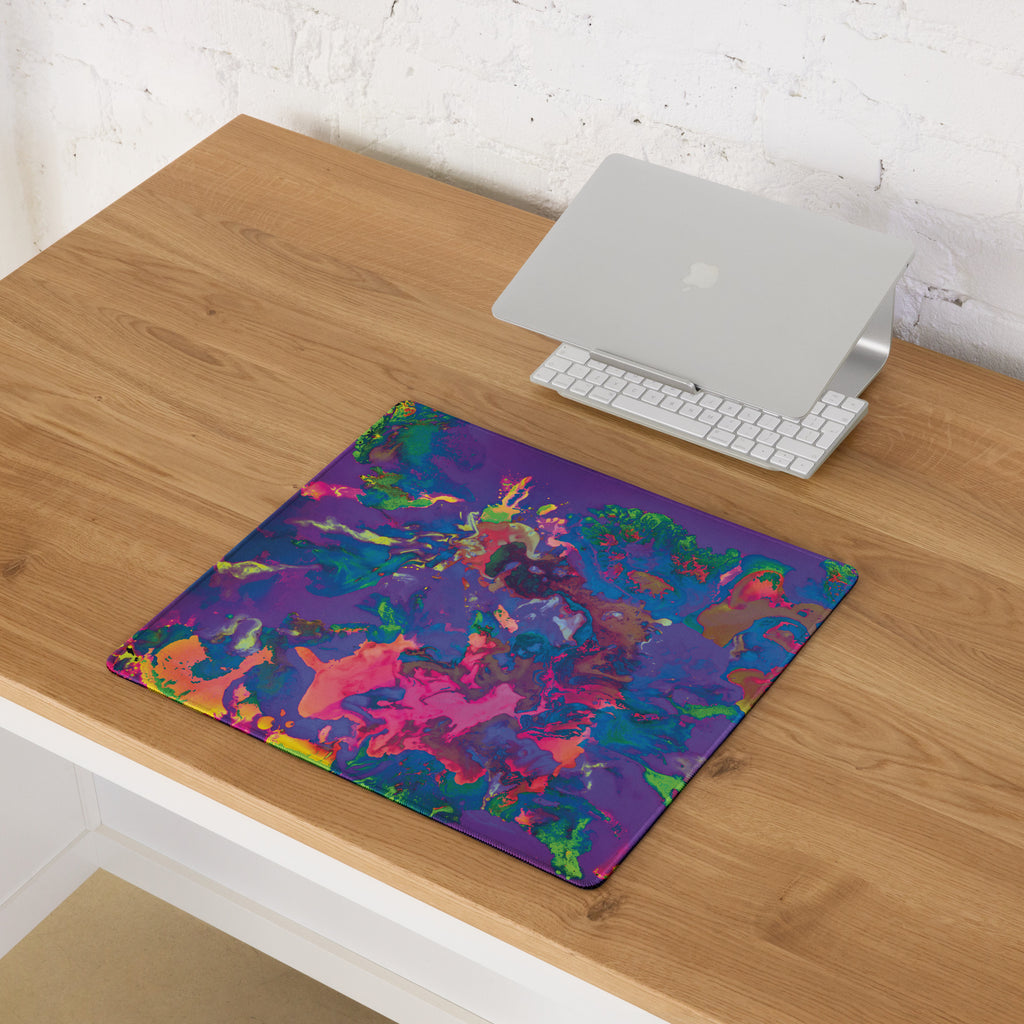Colorful mouse pad on a wooden desk with a laptop and keyboard.