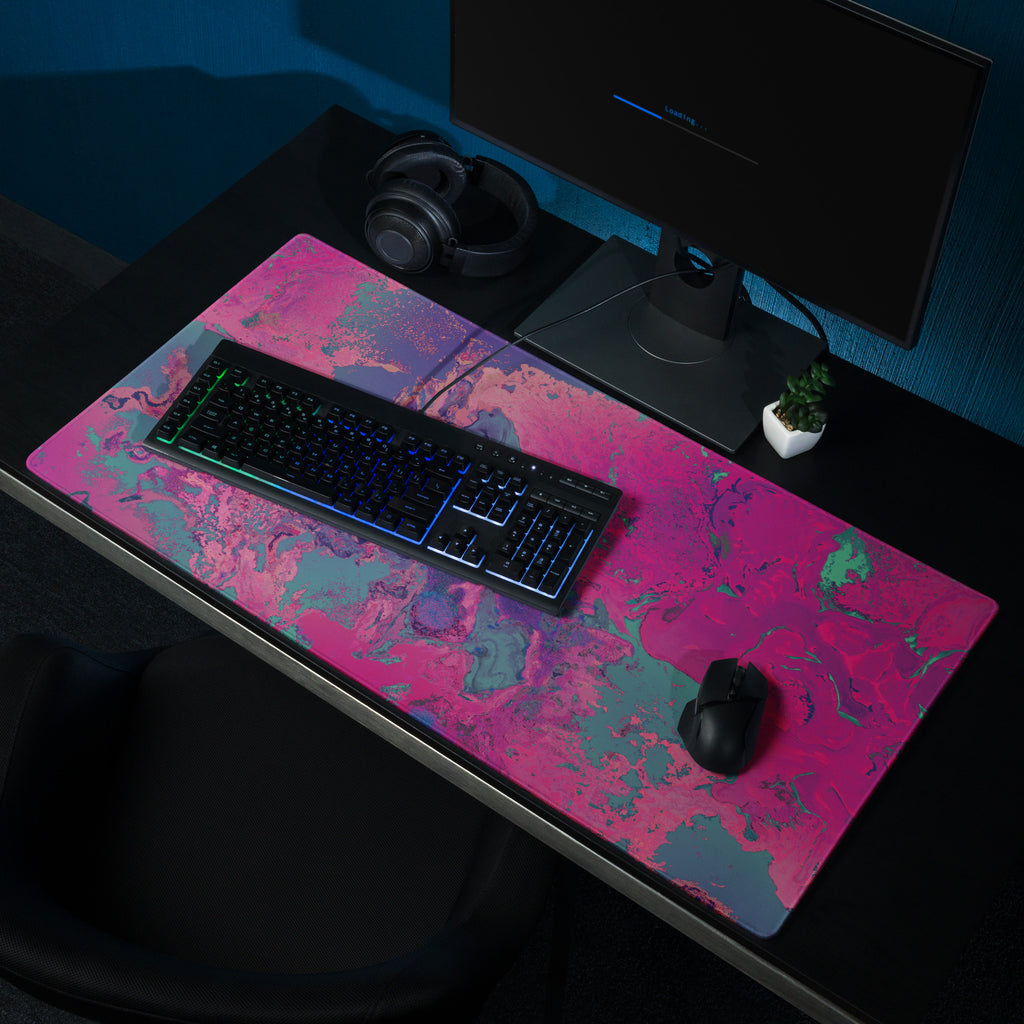 Desk setup with a colorful desk mat, keyboard, mouse, and monitor in a dark room.