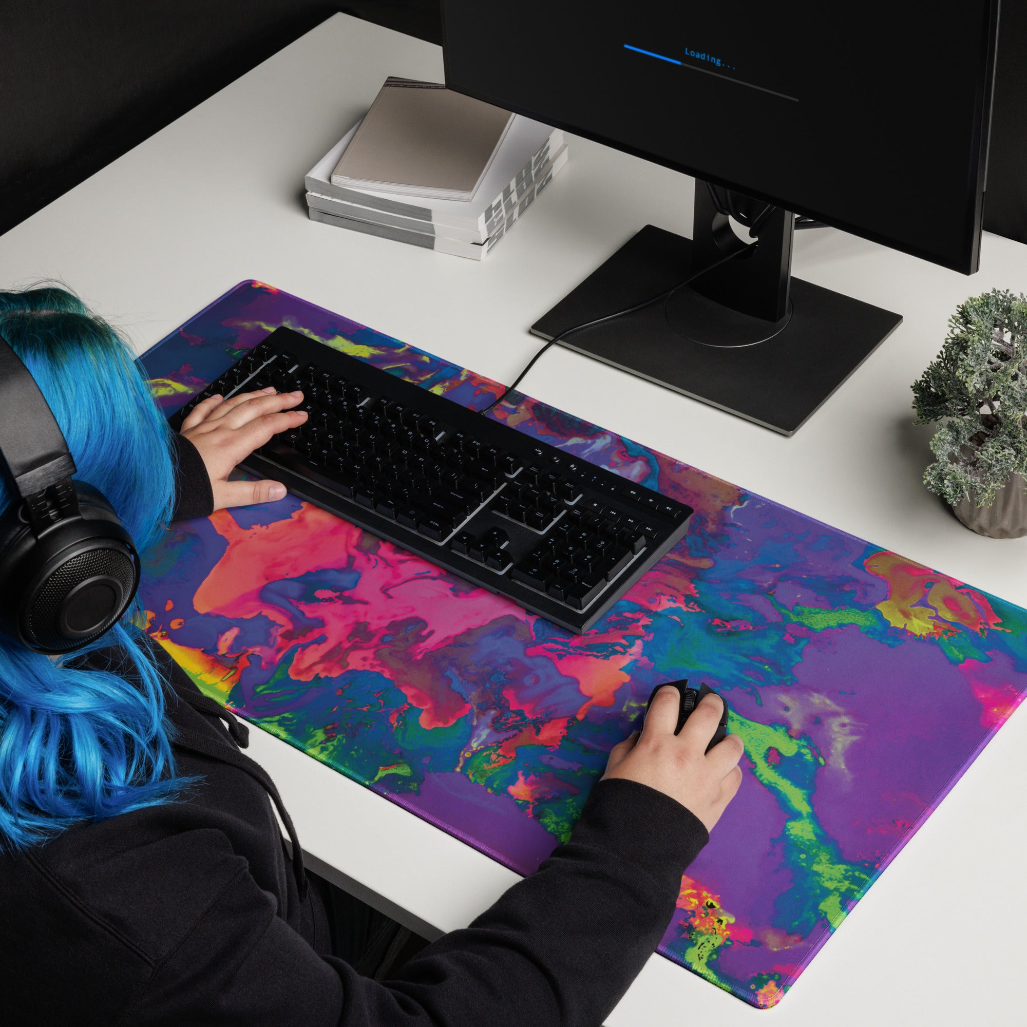 Person using a computer with a colorful desk mat on a white desk.
