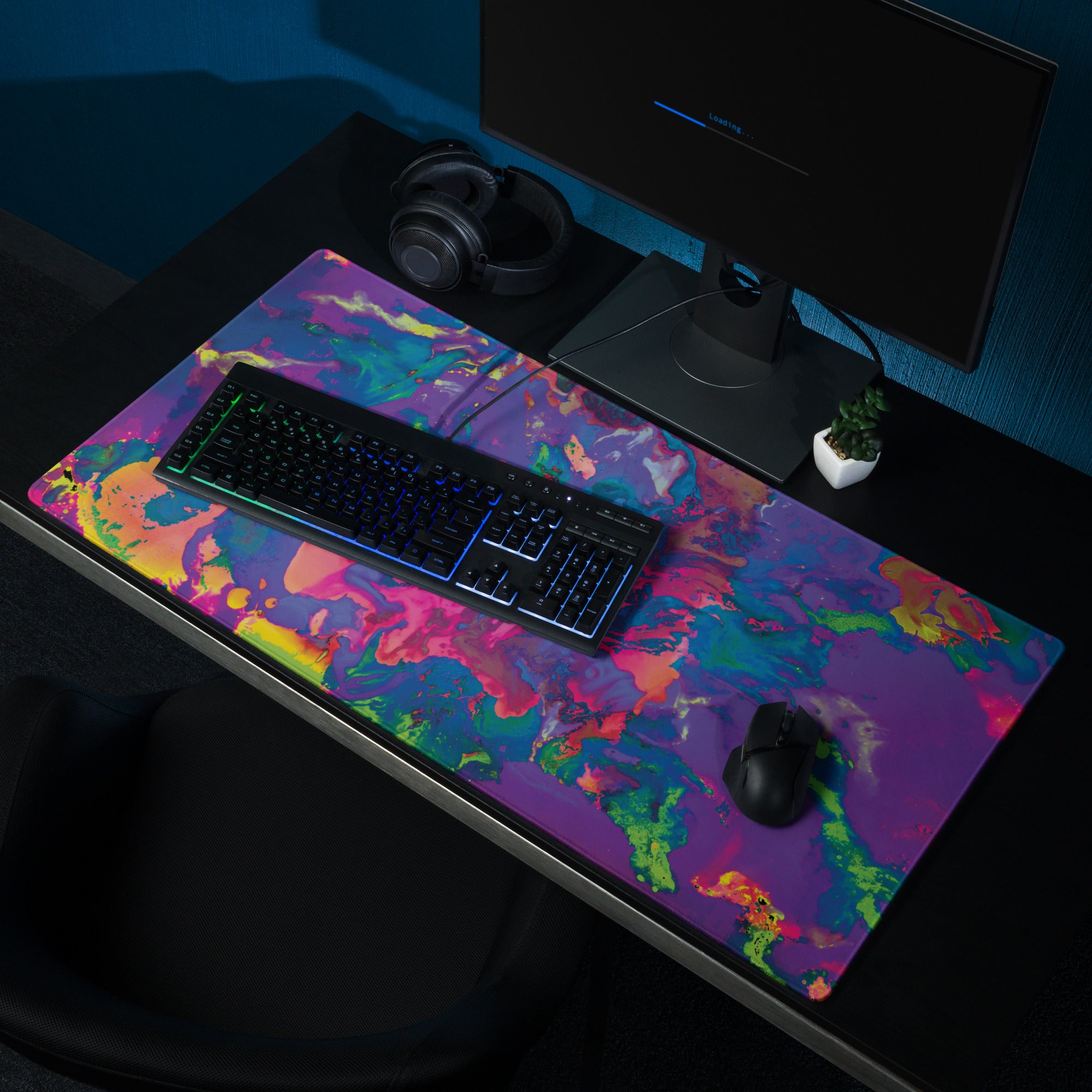 Colorful desk mat with keyboard, mouse, and computer setup on a dark surface.