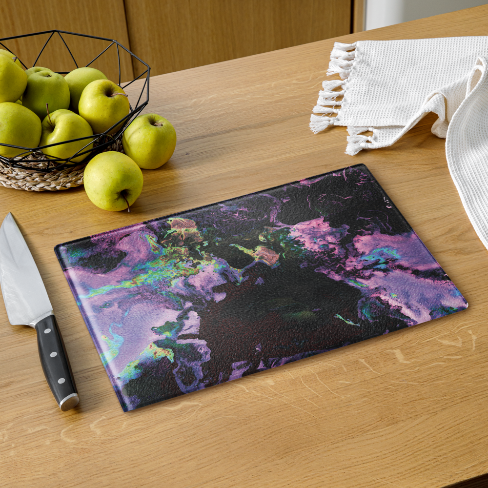 Colorful lavender abstract-patterned glass cutting board on a wooden table with apples and a knife.
