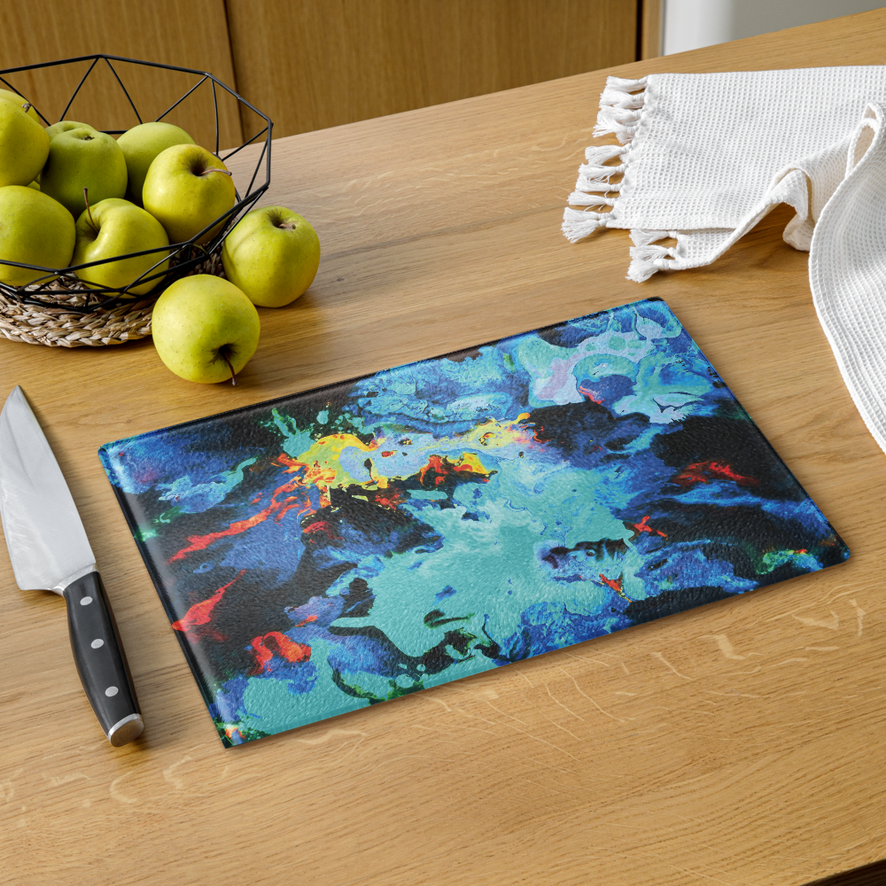 Colorful abstract glass cutting board on a wooden table with apples and a knife.