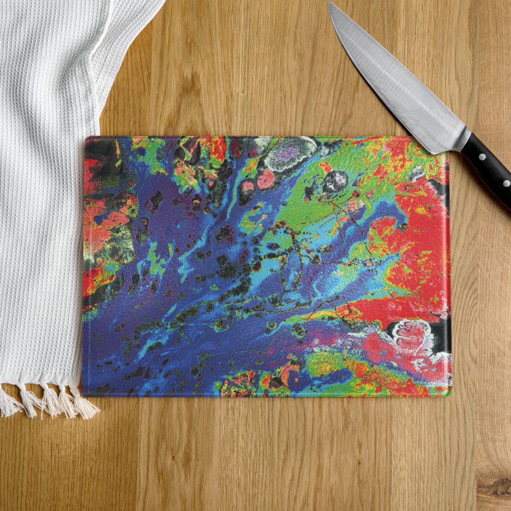 Colorful abstract-patterned glass cutting board with a knife on a wooden surface