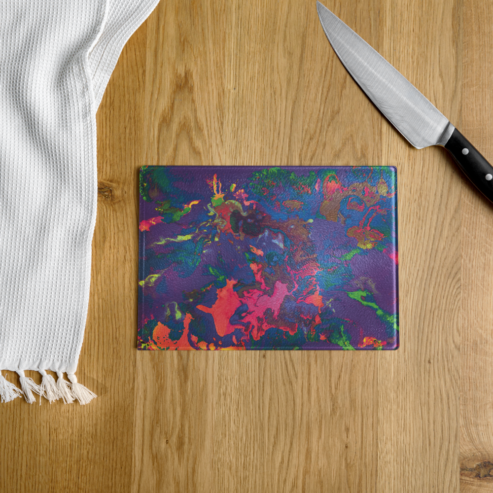 Colorful patterned glass cutting board on a wooden surface with a knife and white towel.