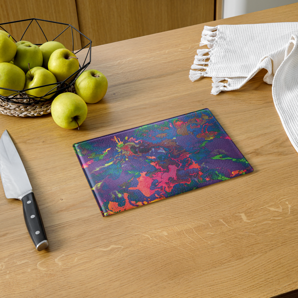 Colorful glass cutting board on a wooden table with apples and a knife.