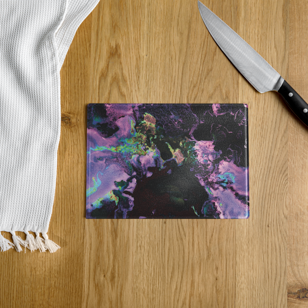 Colorful marbled glass cutting board on a wooden surface with a knife and white towel.