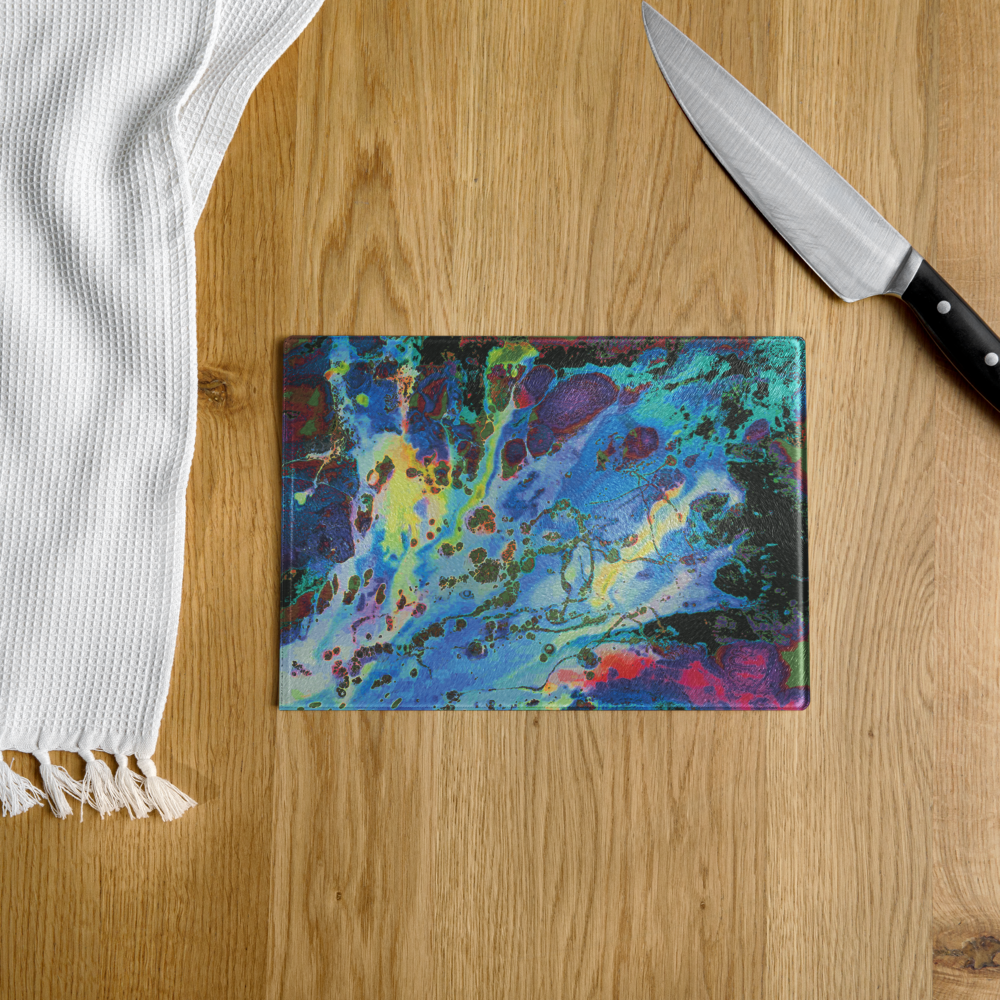 Colorful abstract cutting board on a wooden surface with a knife and white towel.