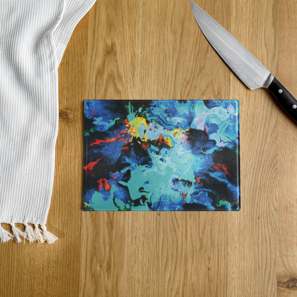 Colorful abstract cutting board on a wooden surface with a knife and white towel.
