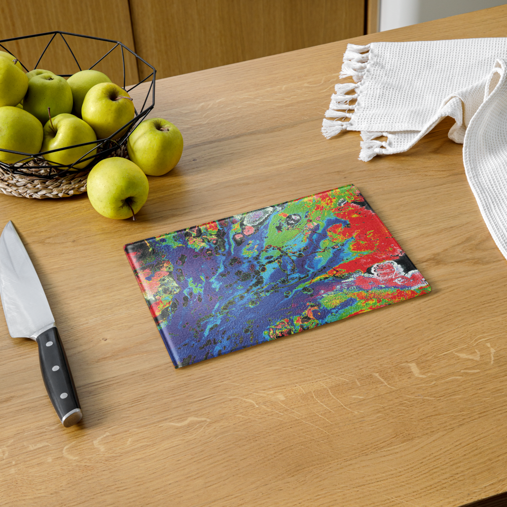 Colorful cutting board on a wooden table with apples and a knife.