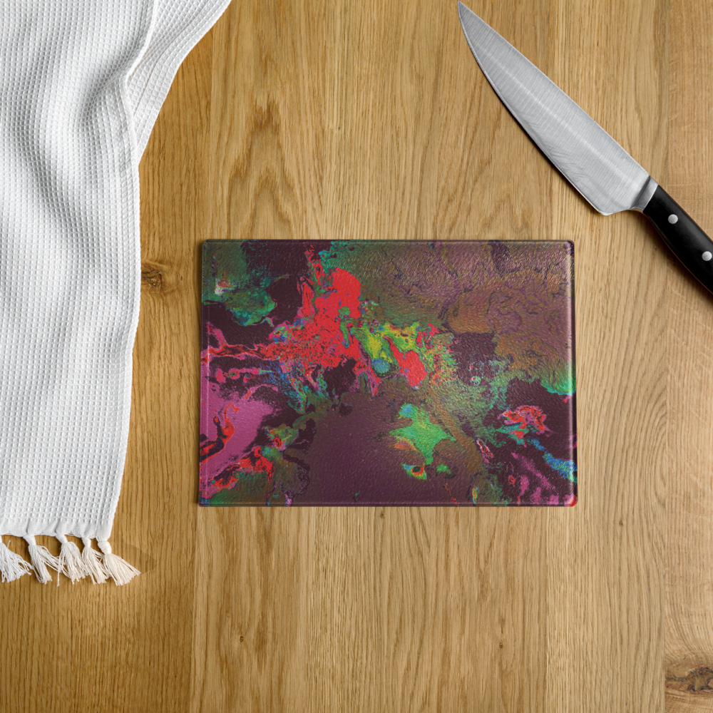 Colorful abstract-patterned cutting board on a wooden surface with a knife and white towel.