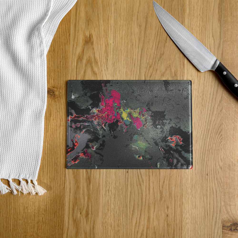 Black marbled cutting board with colorful abstract design on a wooden surface with a knife and white towel.