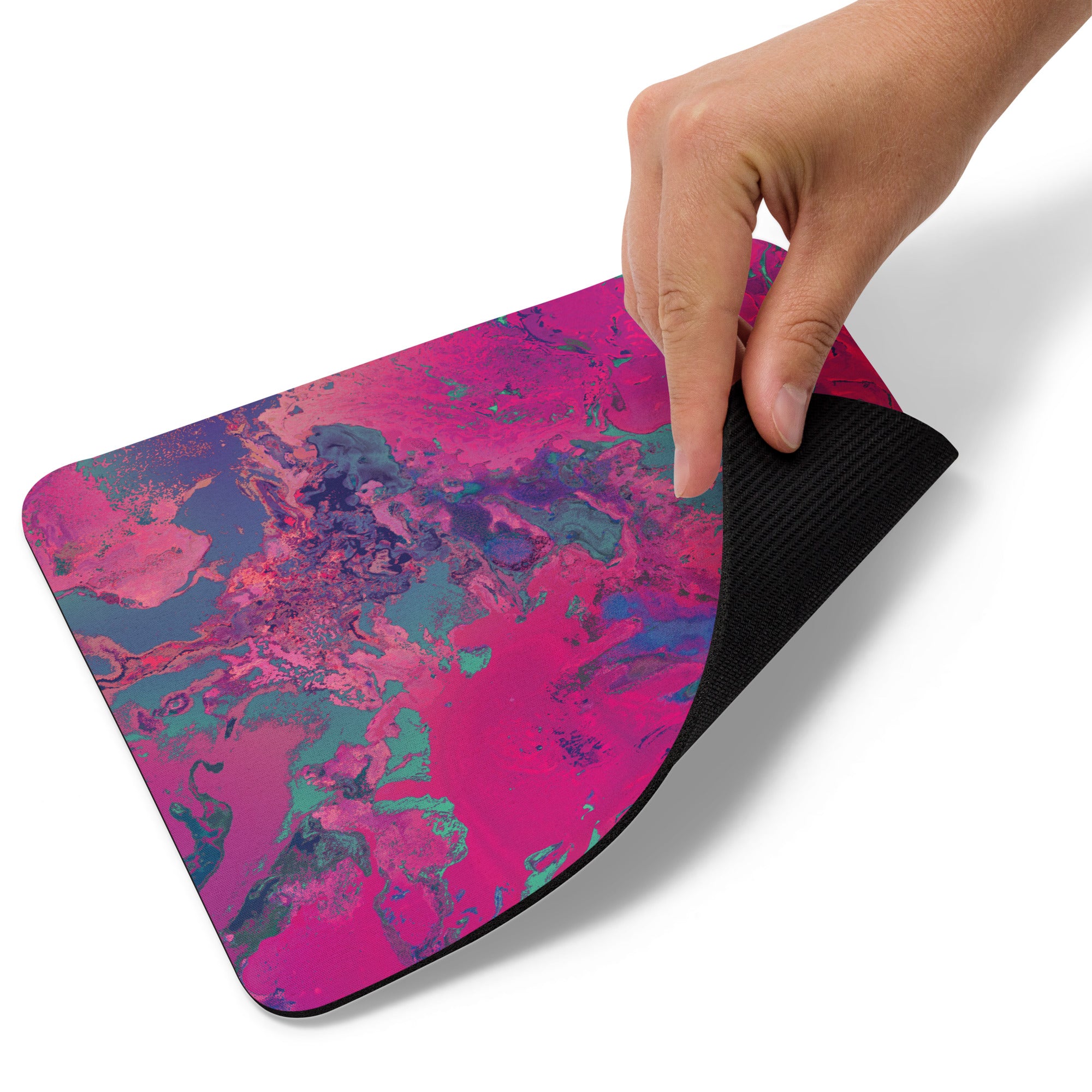 Hand holding a colorful mouse pad with a pink and blue abstract design.