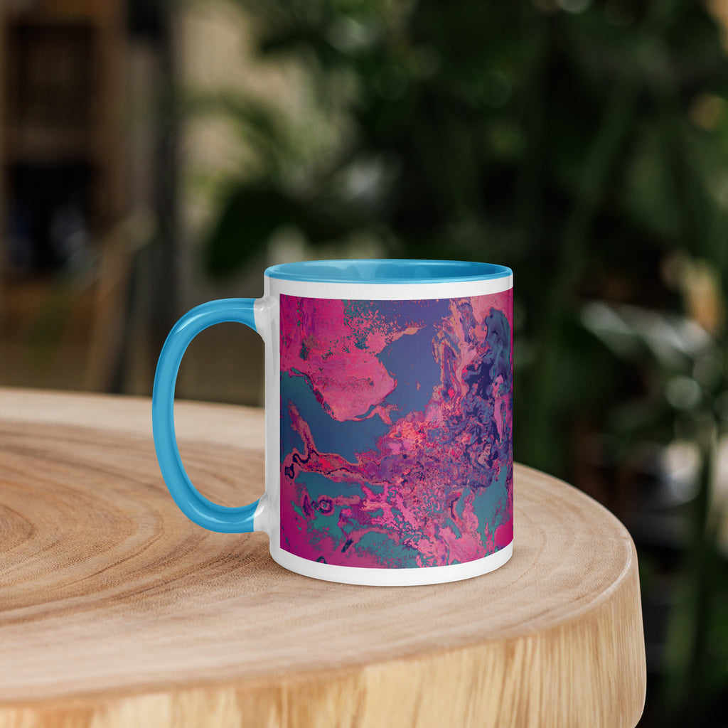 Mug with blue handle and pink abstract design on a wooden surface