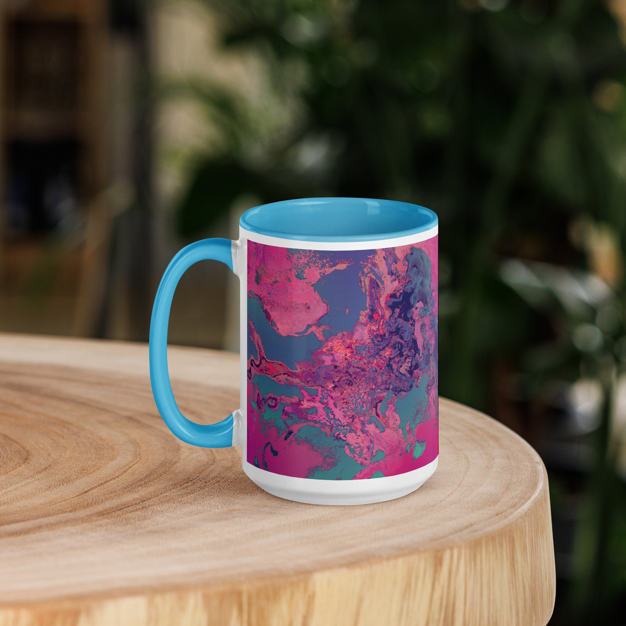 Mug with blue handle and pink abstract design on a wooden surface